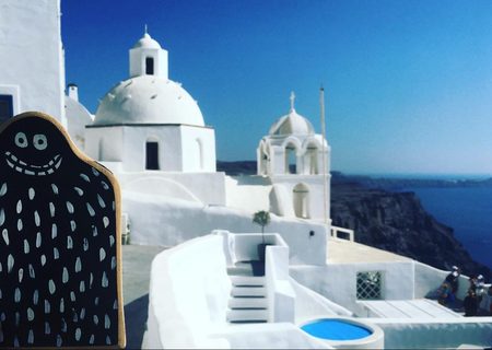 A Lyle held up in front of Santorini